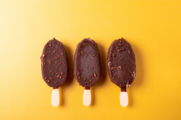tasty cold chocolate ice cream with nuts pieces on wooden stick