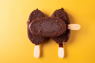 tasty cold chocolate ice cream with nuts pieces on wooden stick