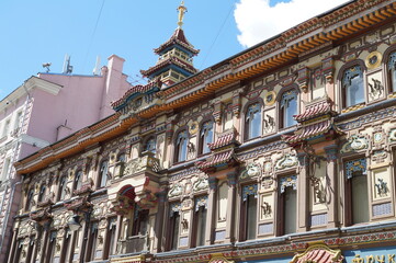 The upper part of the facade of an old building in Chinese style with ornaments against the blue sky
