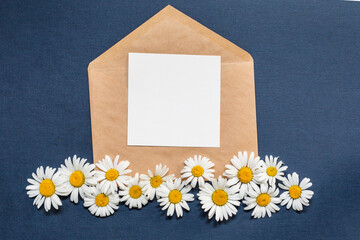 Creative template with a note laying over an craft brown paper envelope. Mockup letter decorated with chamomile flowers