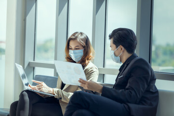 Business workers discussing something and wearing medical face mask for social distancing in new normal situation for virus prevention.