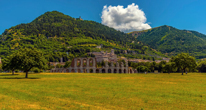 The impressive Roman amphitheater overlooked by Mount Ingino in the city of Gubbio, Italy in summer