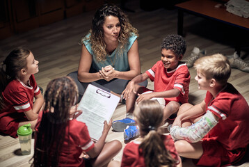 Young woman football trainer talking to team of players.