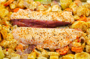 Raw duck breast with vegetables prepared on a metal baking tray