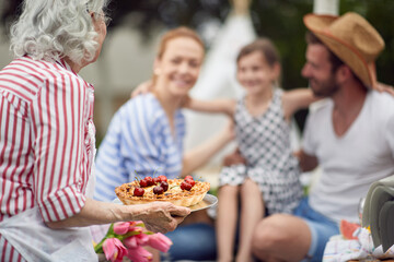 Grandmother prepare pie for family at picnic on backyard.