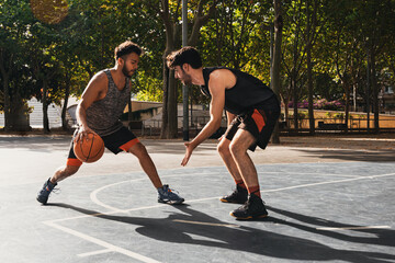 two young men playing basketball outdoors fight for the ball