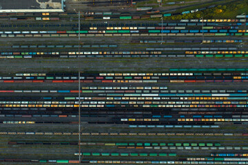 Aerial view of colorful freight trains on the railway station. Wagons with goods on railroad. Heavy industry. Industrial conceptual scene with trains. Top view from flying drone