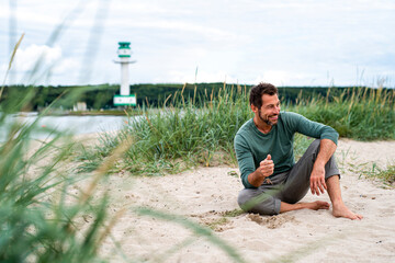 Bärtiger Mann sitzt am Strand in den Dünen