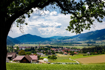 Fototapeta na wymiar gorgeous mountain landscape in the summer with a small city and vivid green meadows