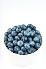 Blueberries are ripe berries in a white Cup on a white background.