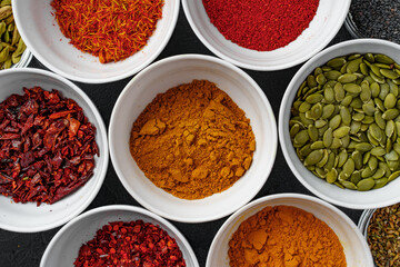 Bowls with assorted spices on dark background