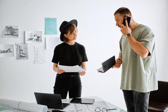 A Young Pretty Girl Designer Shows The Customer A New Project In Office