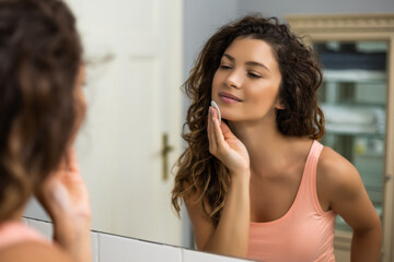 Beautiful brunette woman cleaning her face with cotton pad.	