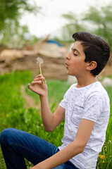 young man blowing dandelion