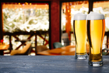 Fresh cold beer on wooden table in pub, space for text