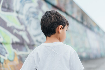 back view of child in white-t-shirt standing outside