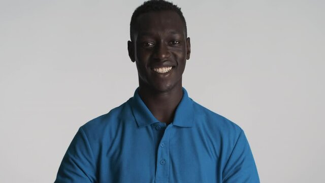 Attractive smiling African American guy happily showing thumb up gesture over gray background. Like expression