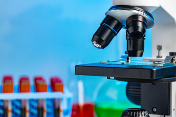 Close up photo of microscope with test tubes with blood samples