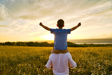 happy family of father and child on field at the sunset having fun