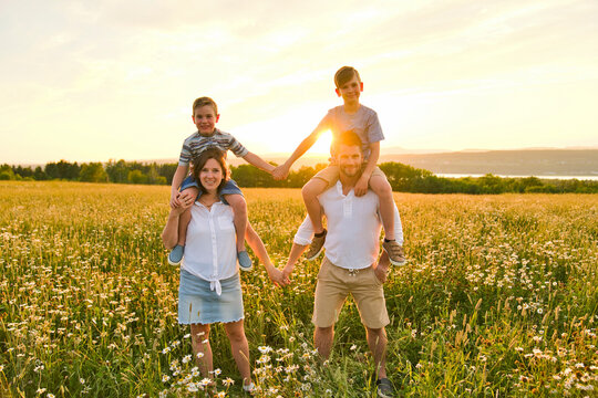 Happy family on daisy field at the sunset having great time together