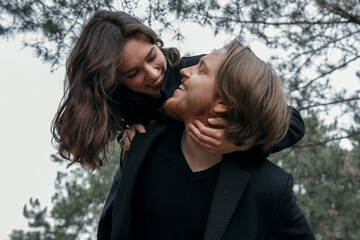 Young couple in the forest. Love story, black coat and dried flowers.