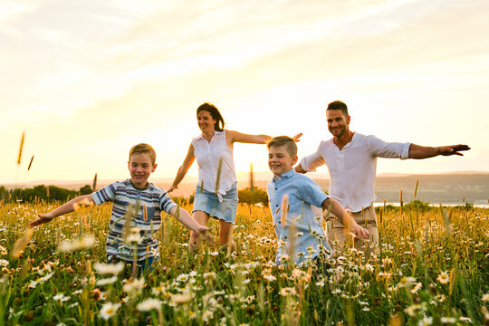 Happy family on daisy field at the sunset having great time together running and fly - Powered by Adobe