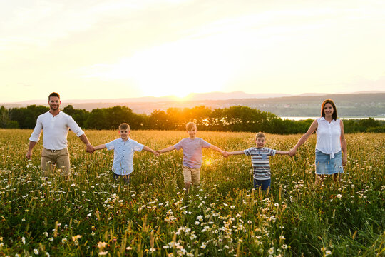 Happy family on daisy field at the sunset having great time together in line