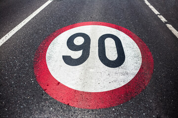 90km/h speed limit sign painted on asphalting road.