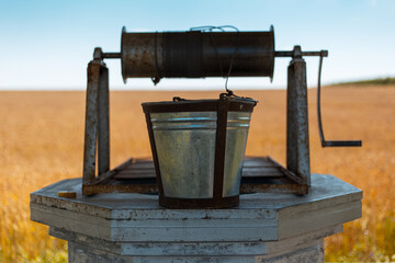 Close-up of ancient water well on background of wheat field.