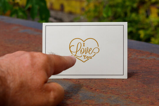 Finger Pointing to Printed Card With Word I Love You Inside Heart Shape