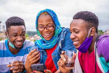 group of young african friends having drinks and using their mobile phones