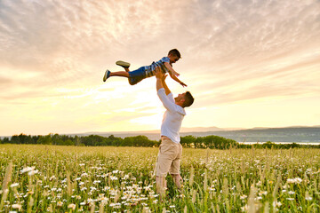 happy family of father and child on field at the sunset having fun - obrazy, fototapety, plakaty