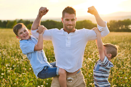 happy family of father and two childs on field at the sunset having fun