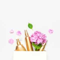 Obraz na płótnie Canvas Cosmetic mock up gold bottles. Cosmetics, white gift bag, pink hydrangea flowers on light background. Cosmetics springtime summer Concept. Flat lay top view. Branding products, spa, beauty background