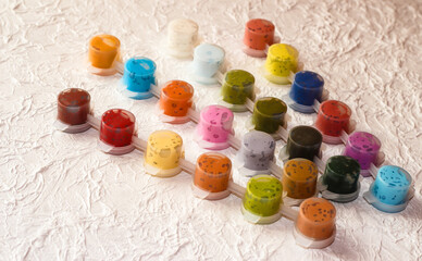 Jars with acrylic paint on a light crumpled background.