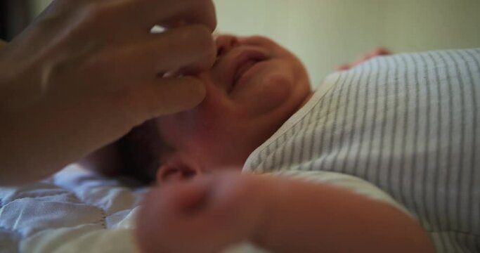 Hands of young mother wiping newborn babys eyes