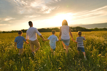 Happy family on daisy field at the sunset having great time together walking field