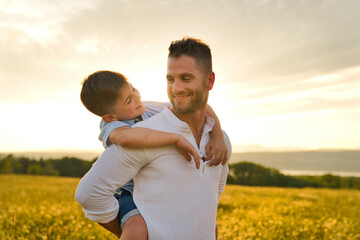 happy family of father and child on field at the sunset having fun