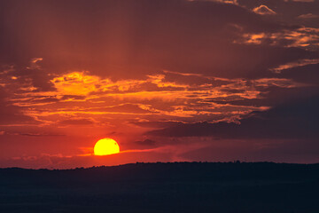 Stunning sunset over Varna suburbs  in the far distance, Bulgaria. Sun hidden behind clouds, rays passing through them. Landscape, cityscape, travel concept. Selective focus, copy space. Silhouettes. 