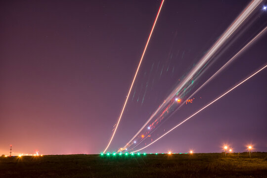 Ligth trails of a taking off airplane on long exposure at night.  horisont litted by the nearby city. Sky covered with shy stars.