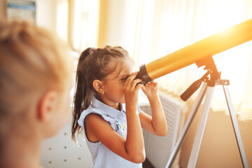 Two schoolgirls are looking through a telescope in an astronomy lesson, back to school, children's...