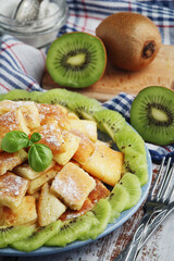 Austrian dessert Kaiserschmarrn served with sugar powder and kiwi fruit