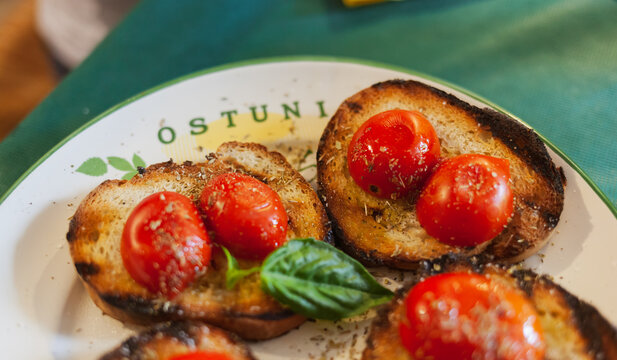 Bruschetta, Italian recipe of the Mediterranean diet. Toasted bread with cherry tomatoes, basil and extra virgin olive oil. Plate of Ostuni