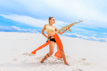 Girls dancers in red skirts and with golden machines in their hands on the beach. White sand and blue sky.