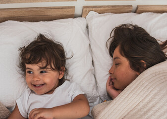 Very happy sisters playing together on their parents bed