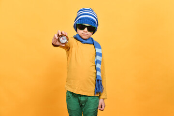 A boy with glasses in a hat and scarf shows a compass.