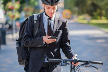 Male bicycle commuter in a suit and helmet with a phone. Cycling around the city, going to office...