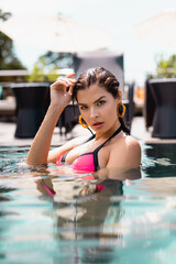 selective focus of attractive woman swimming and looking at camera in swimming pool