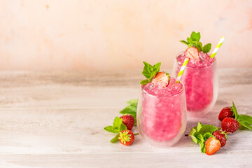 Fresh strawberry cocktail. Fresh summer cocktail with strawberry and ice cubes. Glass of strawberry soda drink on light pink background
