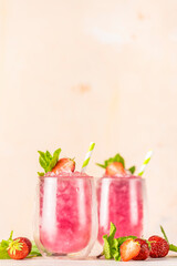 Fresh strawberry cocktail. Fresh summer cocktail with strawberry and ice cubes. Glass of strawberry soda drink on light pink background